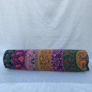 May include: A colorful cylindrical pillow with a patterned design featuring floral and geometric motifs in shades of pink, purple, yellow, green, and blue.