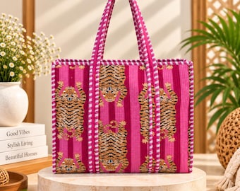 May include: A rectangular tote bag featuring a vibrant magenta and pink vertical striped pattern with a repeating tiger motif. The bag includes two matching magenta and white checkered handles and a coordinating checkered trim along the edges.