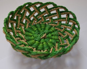 Puede incluir: Una cesta tejida con un patrón verde y marrón natural. La cesta está hecha de finas hebras de material trenzado.