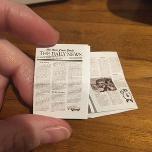 May include: A miniature newspaper called "The Daily News" with the headline "Top News" and "World News". The newspaper is dated Sunday, February 26, 2021.