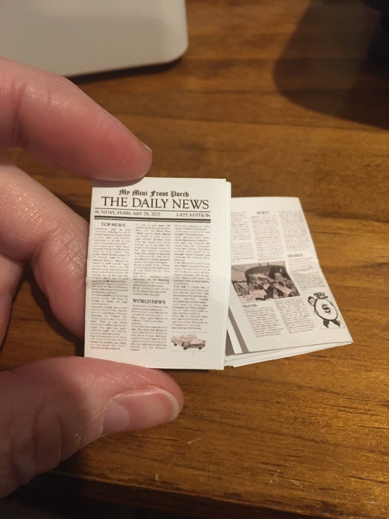 May include: A miniature newspaper called "The Daily News" with the headline "Top News" and "World News". The newspaper is dated Sunday, February 26, 2021.