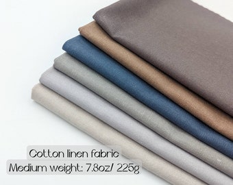 Könnte beinhalten: Ein Stapel Baumwoll-Leinen-Stoff in verschiedenen neutralen Farben, darunter Grau, Blau und Braun. Der Stoff hat ein mittleres Gewicht, etwa 225g. Der Text auf dem Bild lautet "Fat quarter/ half yard/ yards" und "Cotton linen fabric".