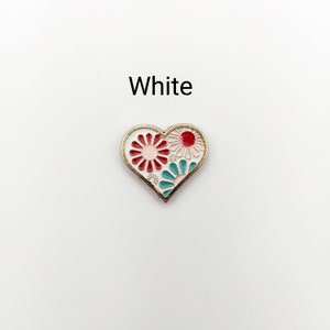 May include: White enamel heart-shaped pin with a red, pink, and teal floral design.
