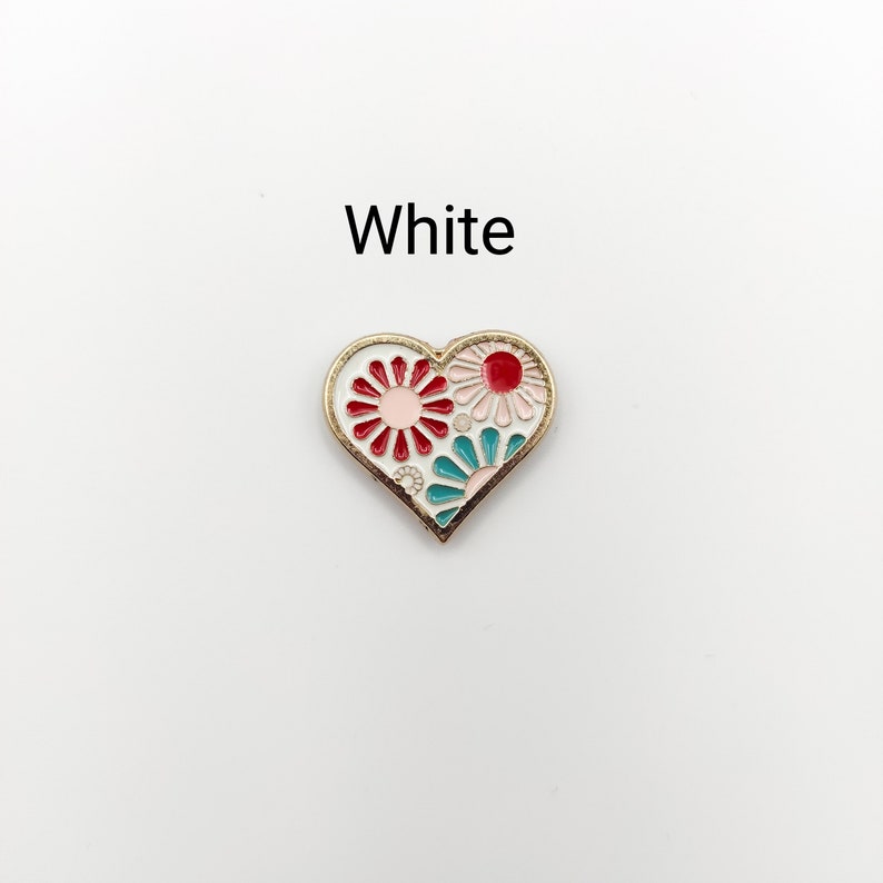 May include: White enamel heart-shaped pin with a red, pink, and teal floral design.