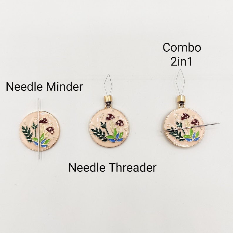 May include: A mushroom-themed needle minder and needle threader combo. The needle minder is a round, cream-colored metal disc with a mushroom design. The needle threader is a small, metal loop with a needle attached to it. The text "Combo 2in1" is written above the needle threader.