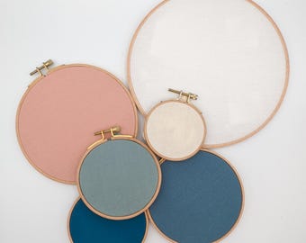 Könnte beinhalten: Fünf Stickrahmen in verschiedenen Größen. Der größte Rahmen ist weiß, der zweitgrößte ist rosa und die drei kleinsten sind blau, hellblau und dunkelblau.