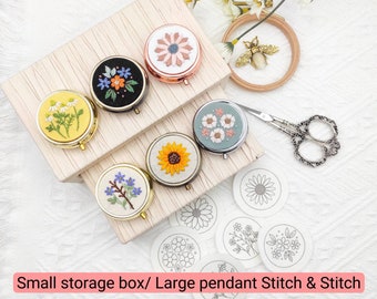 May include: Six small round storage boxes with floral embroidery designs. The boxes are arranged in a pyramid shape on a wooden surface. The boxes are gold, silver, and black. There are also six white circles with floral embroidery designs on a white surface. The text "Small storage box/ Large pendant Stitch & Stitch" is at the bottom of the image.
