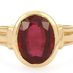 Op de afbeelding: Een gouden ring met een grote, ovaal geslepen, dieprode edelsteen in een gladde zetting. De ringband is gemaakt van gepolijst geelgoud en heeft een eenvoudig, strak ontwerp dat de levendige kleur van de centrale steen mooi naar voren brengt.