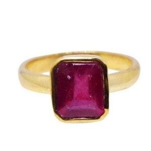 Op de afbeelding: Een gouden ring met een rechthoekige, dieproze edelsteen gezet in een gladde, gepolijste gouden band. De steen heeft een gefacetteerd oppervlak en wordt vastgehouden door een eenvoudige zetting, wat zorgt voor een strakke en klassieke uitstraling.