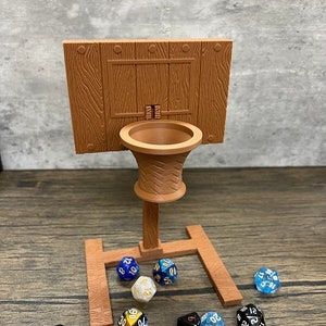 May include: A wooden basketball hoop with a brown net and a set of colorful dice scattered around the base. The dice are various colors, including blue, black, white, and gold.