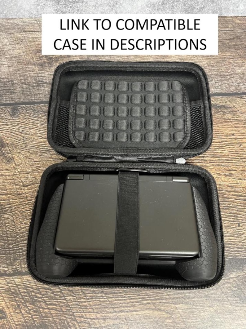 May include: A black zippered carrying case containing a black handheld gaming console with a textured grip. The interior lid features a padded grid section and a mesh pocket. Text at the top reads: LINK TO COMPATIBLE CASE IN DESCRIPTIONS.