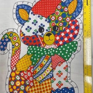 May include: A colorful patchwork cat design on white fabric, featuring various patterns like polka dots, floral prints, and gingham. The cat has a green bow tie and is outlined with black stitching. Text at the bottom reads "LEAVE OPEN FOR STUFFING".