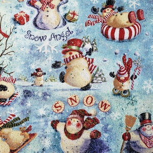 Könnte beinhalten: Ein blauer und weißer Stoff mit einem Winterthema mit Schneemännern. Die Schneemänner sind in verschiedenen Winteraktivitäten beschäftigt, darunter das Bauen eines Schneemanns, Schlittenfahren und Schneeballschlachten. Der Stoff zeigt auch das Wort "SNOW" in roten Buchstaben.