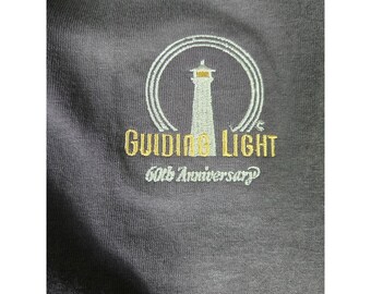 Vintage Guiding Light T-shirt uit 1997, ter ere van het 60-jarig jubileum. Verkrijgbaar in maat XL voor heren of dames.