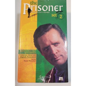 May include: A rectangular DVD box set titled The Prisoner Set 2 featuring a portrait of Patrick McGoohan. The cover is split into orange and green sections with text stating Television's First Masterpiece, Complete, Uncut and Digitally Remastered.
