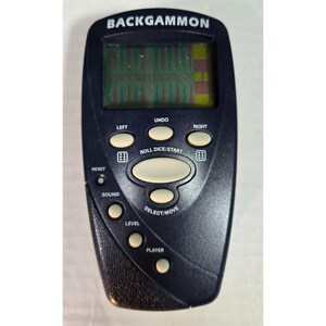 May include: A handheld electronic Backgammon game featuring a dark blue plastic casing with a digital screen. The device includes light-colored control buttons labeled LEFT, UNDO, RIGHT, ROLL DICE/START, RESET, SOUND, LEVEL, SELECT/MOVE, and PLAYER.