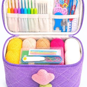 May include: A purple quilted storage case containing a variety of crochet supplies. The interior features slots for colourful crochet hooks, metal needles, and plastic stitch markers. The main compartment holds several balls of yarn and a clear box.