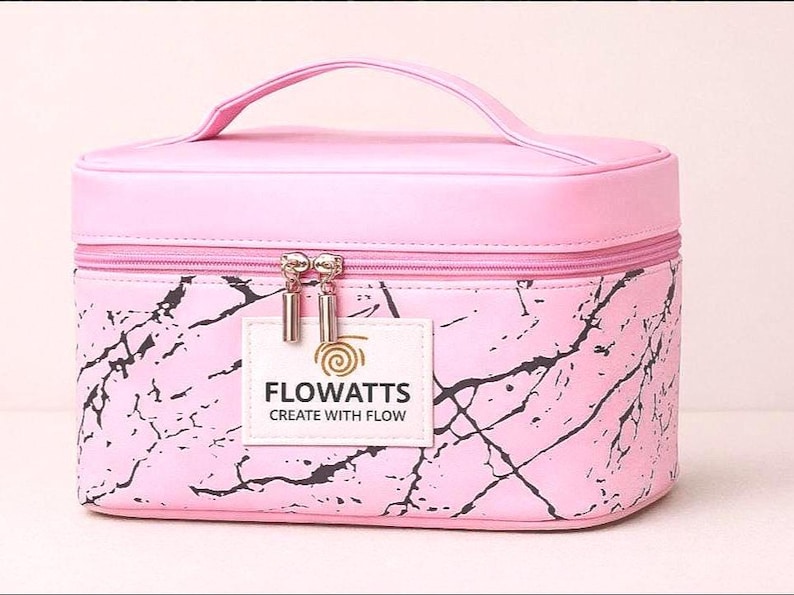 Pode incluir: Bolsa de maquilhagem rosa com pega e padr&atilde;o marmoreado. A bolsa tem fecho de correr e uma pequena etiqueta com a inscri&ccedil;&atilde;o "FLOWATTS CREATE WITH FLOW". Concebida para guardar cosm&eacute;ticos e produtos de beleza.