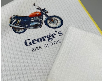May include: White microfiber cleaning cloths with yellow edging. One cloth has a printed image of a motorcycle and the text "George's Bike Cloths".