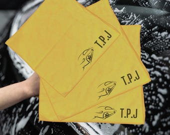 May include: Three yellow microfiber cloths with a black car silhouette and the text "T.P.J." printed on them.