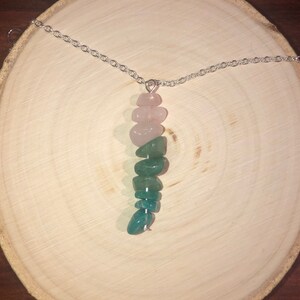 May include: A silver chain necklace with a pendant made of pink and green stones. The stones are arranged in a graduated pattern, with the pink stones at the top and the green stones at the bottom.