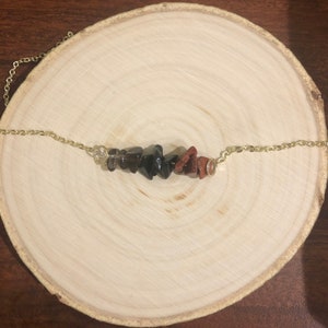 May include: A gold chain necklace with a row of brown, black, and red gemstone chips.