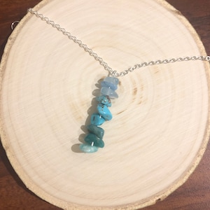 May include: A silver chain necklace with a pendant made of layered blue and turquoise stones.