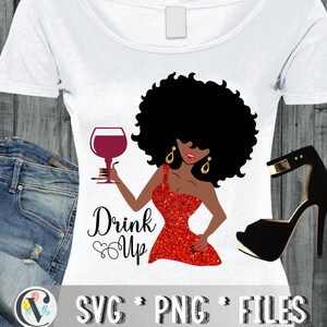 May include: A digital design featuring a black woman with an afro holding a glass of red wine. The text "Drink Up" is written below the woman. The design is on a white t-shirt with a pair of blue jeans and a black high-heeled shoe.