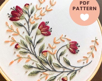 May include: An embroidery hoop containing white fabric with a floral design featuring dark red flowers, sage green leaves, and light orange sprigs. Small metallic beads are scattered throughout. The text reads BELLA SAVOY and PDF PATTERN.