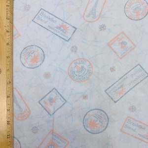 May include: White fabric with a repeating pattern of blue and orange stamps. The stamps feature text such as "Breakfast Blend", "Mountain Grown", "House Rich Blend Coffee", "Royal Kona Hawaii", and "Hand Picked".