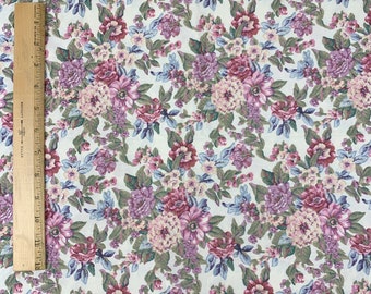 May include: White fabric with a floral pattern featuring pink, purple, and blue flowers. The fabric has a vintage aesthetic.