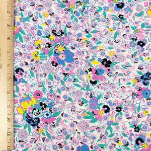 May include: White fabric with a floral print featuring pink, blue, and green flowers on a white background.