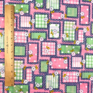 May include: Pink and green fabric with a patchwork design featuring white flowers and a variety of patterns including gingham, polka dots, and stripes. The fabric is framed with a blue and white lace trim.