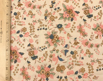 May include: A cream-colored fabric with a floral pattern. The pattern features pink, brown, and blue flowers with green leaves. The fabric is perfect for crafting projects, quilting, or making clothing.