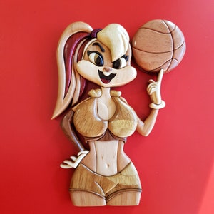 May include: A wooden carving of a cartoon bunny wearing a basketball uniform and holding a basketball. The bunny is brown and white with a red and white striped tail.