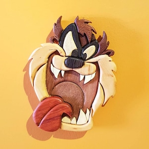 May include: A wooden carving of a cartoon Tasmanian devil with a wide open mouth and a red tongue sticking out. The devil has brown fur and a black nose.