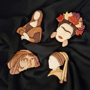 May include: Four wooden sculptures of famous women, including the Mona Lisa, Frida Kahlo, and the Girl with a Pearl Earring. The sculptures are intricately carved and painted in shades of brown, red, and white.