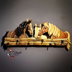 May include: Wooden wall-mounted coat rack featuring three intricately carved horses' heads. The horses are brown, light brown, and white, with a natural wood finish. The rack has five hooks for hanging coats, hats, or other items.