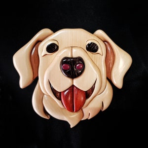 以下が含まれることがあります： 明るい茶色、ベージュ、濃い茶色のカラーリングで、ラブラドールレトリバーの犬の木彫り。犬は舌を出して幸せそうな表情をしている。