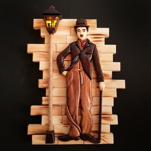 Puede incluir: Una escultura de pared de madera de un hombre con traje y sombrero, sosteniendo un bastón, de pie junto a una farola. La escultura está hecha de madera y tiene un aspecto realista.