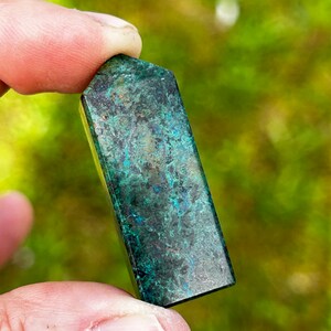 May include: A green and blue azurite crystal tower with a smooth, polished finish. The crystal has a unique, marbled pattern.