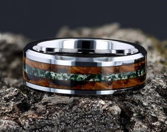 May include: A silver tungsten carbide ring with a brown and green wood inlay. The ring has a beveled edge and a polished finish.