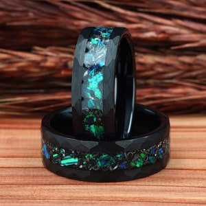 May include: Two black tungsten carbide rings with a green and black opal inlay. The rings are stacked on top of each other.