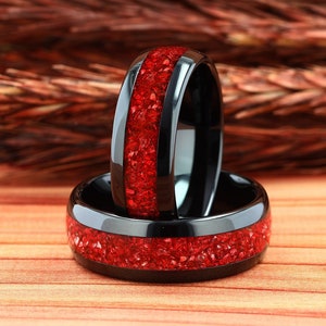 May include: Two black ceramic rings with a red inlay. The rings are stacked on top of each other.