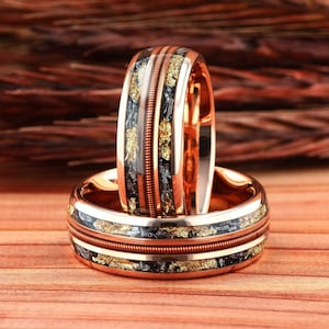 May include: Two copper wedding bands with a black and gold inlay. The bands are stacked on top of each other.