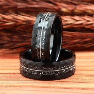 May include: Two black tungsten carbide rings with a hammered finish and a silver inlay. The rings are stacked on top of each other.