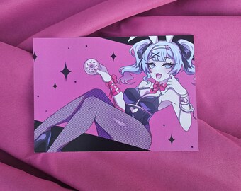 May include: A pink art print featuring an anime-style character with light blue hair and bunny ears. The character is wearing a black outfit and holding a donut. The background is pink with black star shapes.