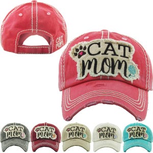 May include: A red distressed baseball cap featuring a frayed beige patch on the front with the black text CAT MOM, a paw print with a pink heart, and a ball of yarn. The back of the cap also displays the text CAT MOM in white embroidery.