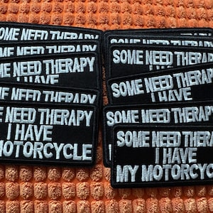 Puede incluir: Parches rectangulares negros con texto bordado en blanco. El texto en los parches dice "SOME NEED THERAPY I HAVE MY MOTORCYCLE". Los parches están sobre una superficie naranja texturizada.