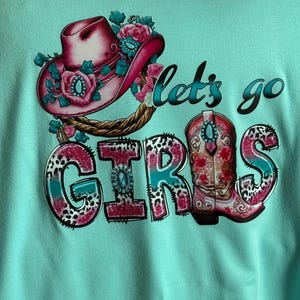 Lass uns gehen Mädchen mit aquamarin und rosa Schrift, Stiefel auf dem Boden Tshirt